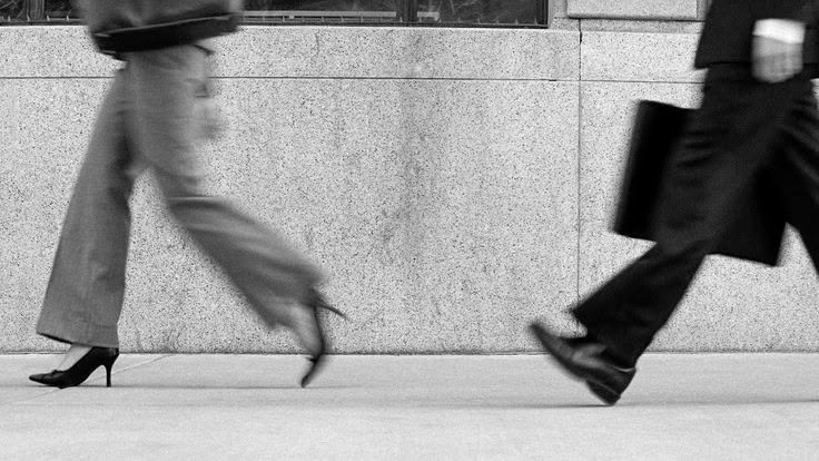 Personas caminando apresuradas por una calle urbana en blanco y negro