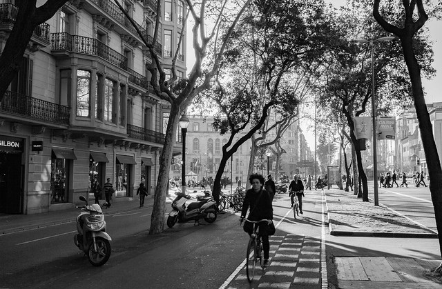 Personas en bicicleta por un carril bici urbano en blanco y negro
